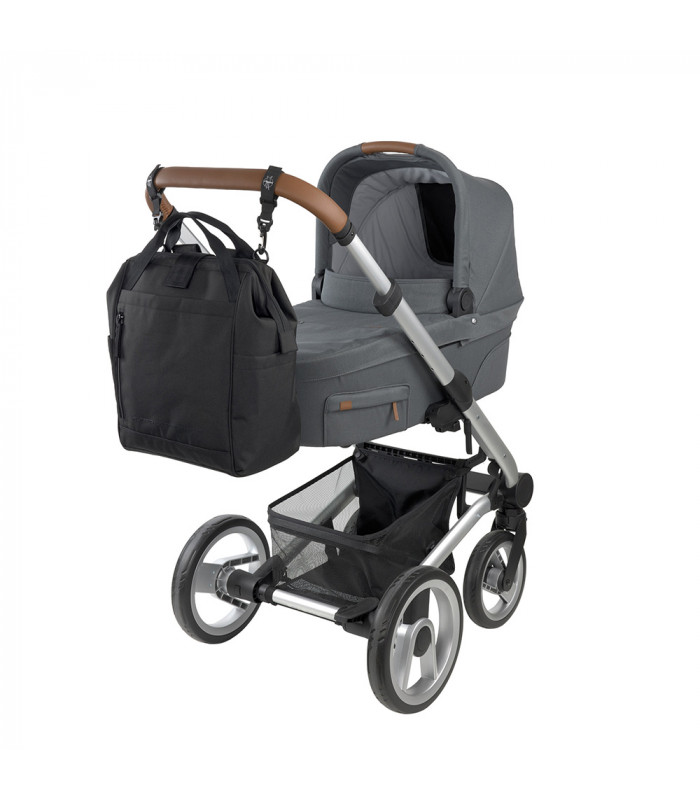 Mochila maternal Goldie Up Lässig negra de tela, colgada del manillar de un cochecito de bebé gris y moderno.