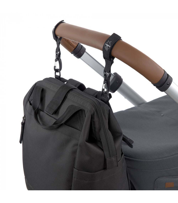 Mochila maternal Goldie Up Lässig negra de tela, colgada con ganchos del manillar de un cochecito de bebé.