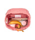 Interior de la mochila mini outdoor Lässig rosa con un plátano, una manzana y un libro en su compartimento.