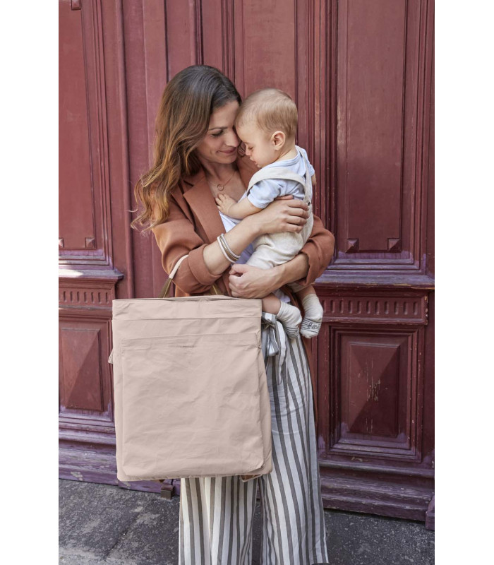 Mochila Tyve Lässig beige de forma rectangular y material arrugado, mostrada por una mujer que sostiene a un bebé.