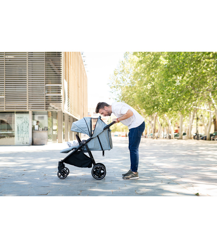 Silla de paseo VentT+ Niu gris con chasis negro y capota amplia, manejada por un hombre en un entorno exterior soleado.