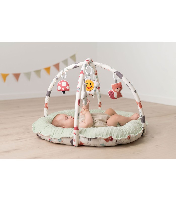 Gimnasio de bebé Olmitos con base circular acolchada verde menta, arcos blancos y juguetes de peluche colgantes.