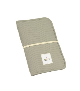 Cambiador Lässig plegado de color verde grisáceo con textura de rayas, banda elástica de cierre y logo en parche blanco.