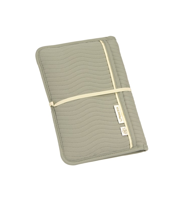 Cambiador portátil Lässig de color gris claro, plegado en forma rectangular con una cinta elástica blanca de cierre.