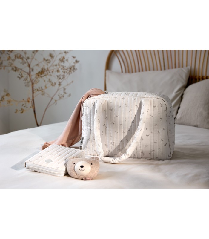 Portadocumentos Lässig rectangular en tela gris suave con motas, acompañado de un bolso y un peluche sobre una cama.