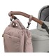 Mochila maternal Minoa de tela rosa palo, colgada mediante ganchos del manillar marrón de un cochecito gris.